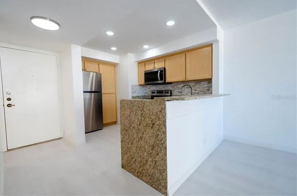 A modern kitchen with granite countertops, stainless steel appliances, and wooden cabinets.