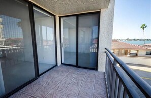 Ein Balkon mit Glasüren, gefliestem Boden und Blick auf ein Gewässer sowie Gebäude.