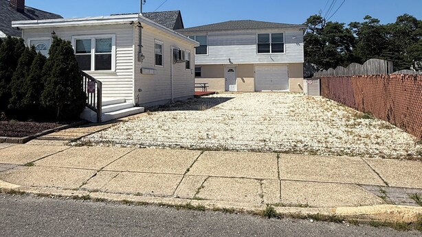 A two-story residential building with a garage, a covered driveway, and a fenced yard.