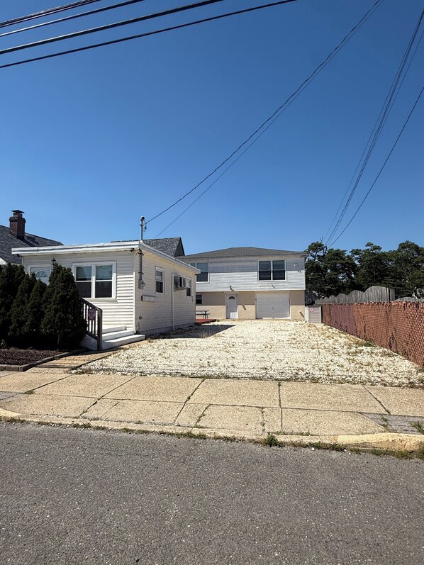 A two-story residential building with a garage, a covered driveway, and a fenced yard.