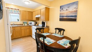 A compact kitchen with wooden cabinets, a white stove, and a dining table with four chairs.