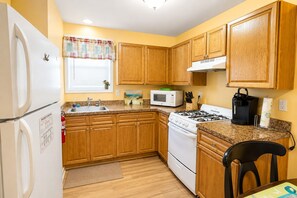 A compact kitchen with wooden cabinets, a white refrigerator, a microwave, a stove, and a sink. - Seaside Heights 1BR Getaway • Parking + Beach Badges  (Seaside Heights)