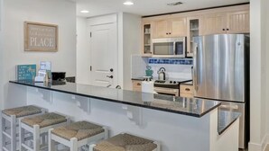 Uma cozinha moderna com ilha central, eletrodomésticos de aço inoxidável e armários em madeira clara.
