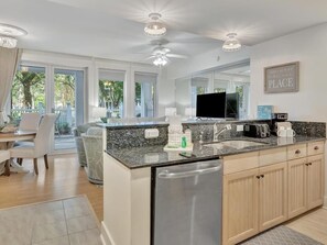 A modern kitchen with a dishwasher, double sink, and a dining area with a table and chairs. - Observation Point 359 - Sandestin Retreat (Miramar Beach)