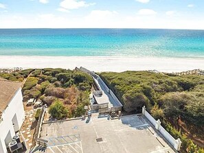 Luftaufnahme eines Küsteneigentums mit befestigter Fläche, einem weißen Gebäude und einem Strand im Hintergrund.