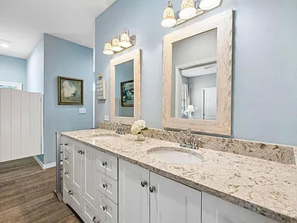 A bathroom with a double sink vanity, a large mirror, and a light fixture above the mirror.