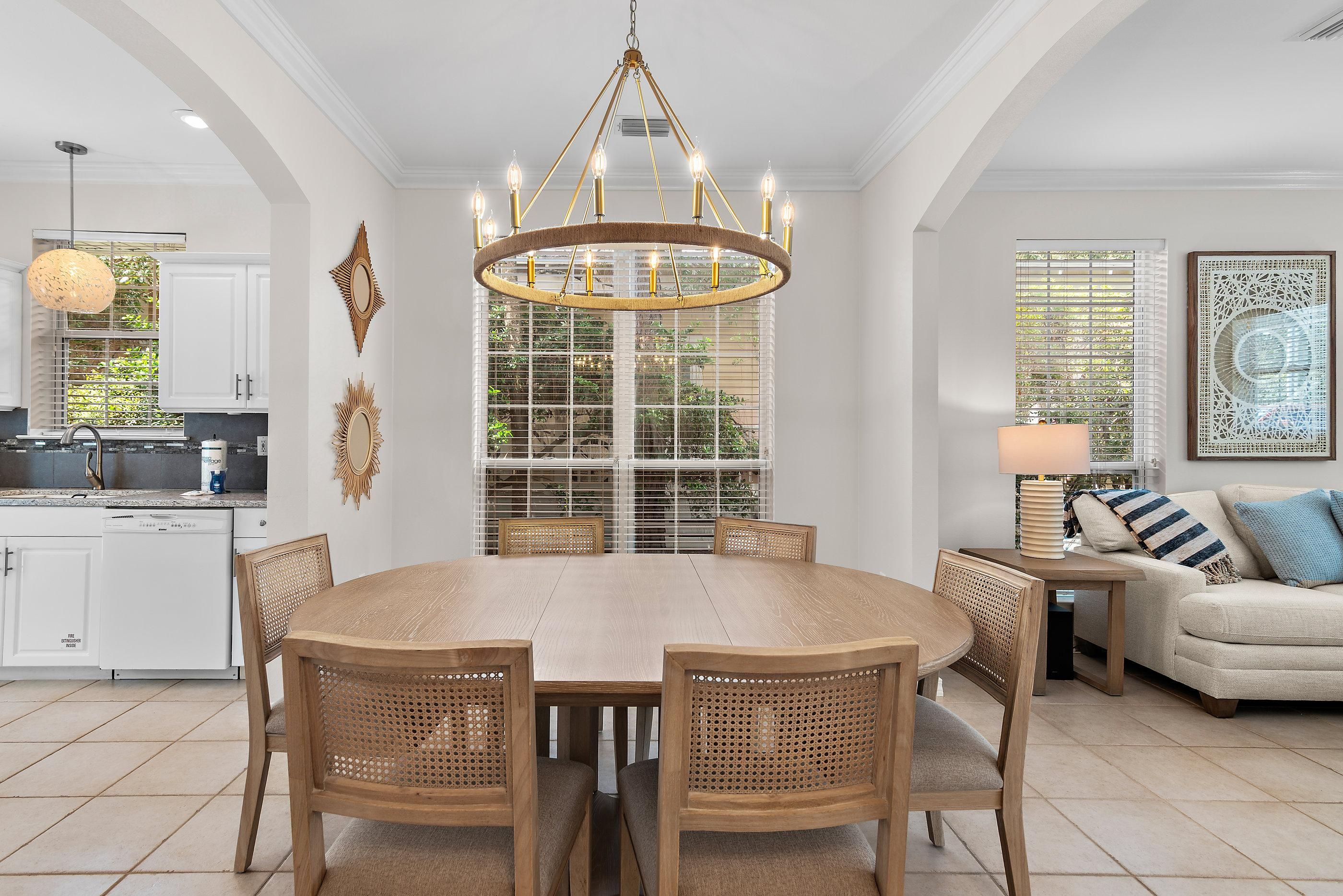 A dining area with a round table, chairs, and a chandelier.