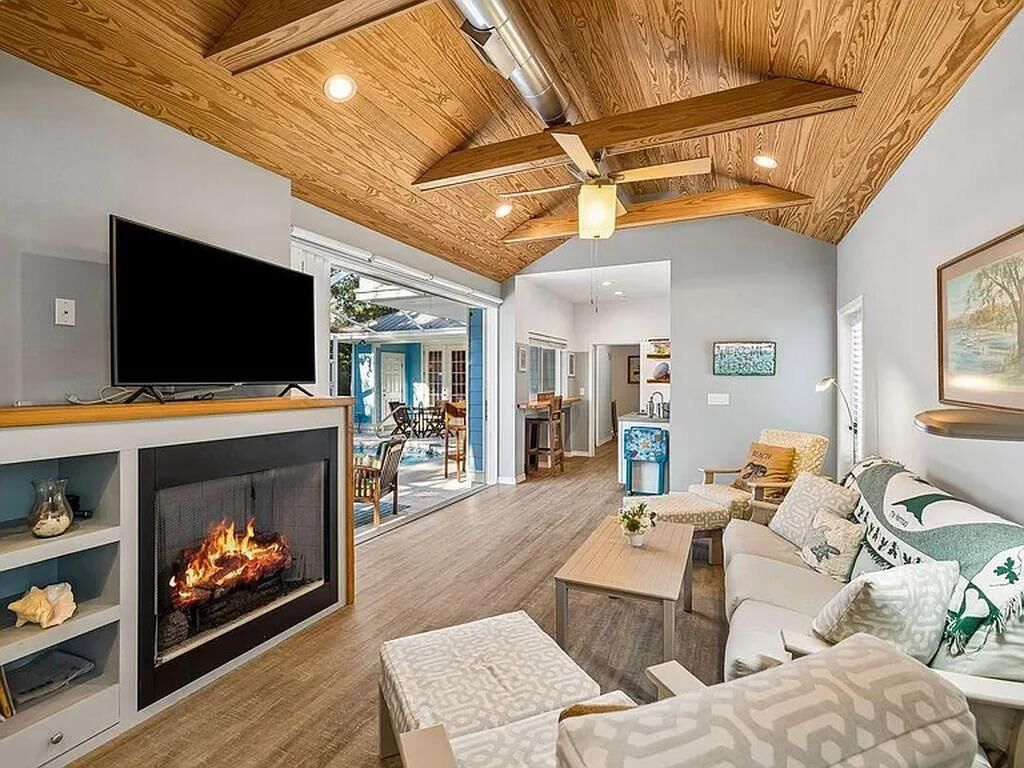 Un salon avec une cheminée, un téléviseur et un ventilateur de plafond.