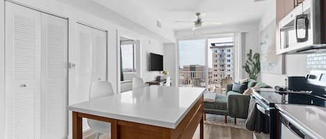 Cozinha moderna com área de jantar, televisão e varanda com vista para a cidade.