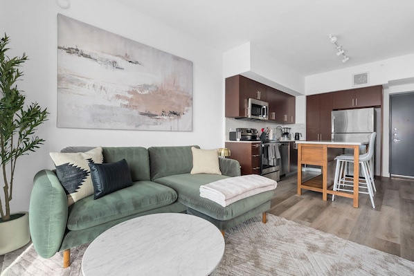 A modern living room with a green sofa, a white coffee table, and a large abstract painting on the wall. - Lodgeur Denton (Denton)