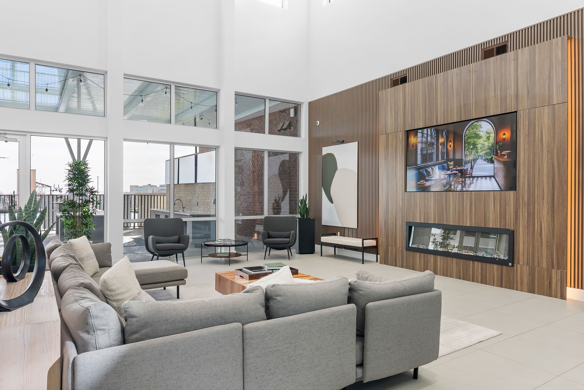 A modern interior with a grey sectional sofa, a coffee table, and a TV mounted on a wooden wall.