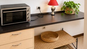 Eine Küchenzeile mit Backofen, einer roten Lampe und einem Blumentopf auf der Arbeitsplatte.