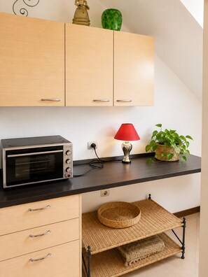 Eine Küchenzeile mit Backofen, einer roten Lampe und einem Blumentopf auf der Arbeitsplatte.