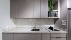 Uma cozinha moderna com uma geladeira de aço inoxidável, um micro-ondas e uma pia.