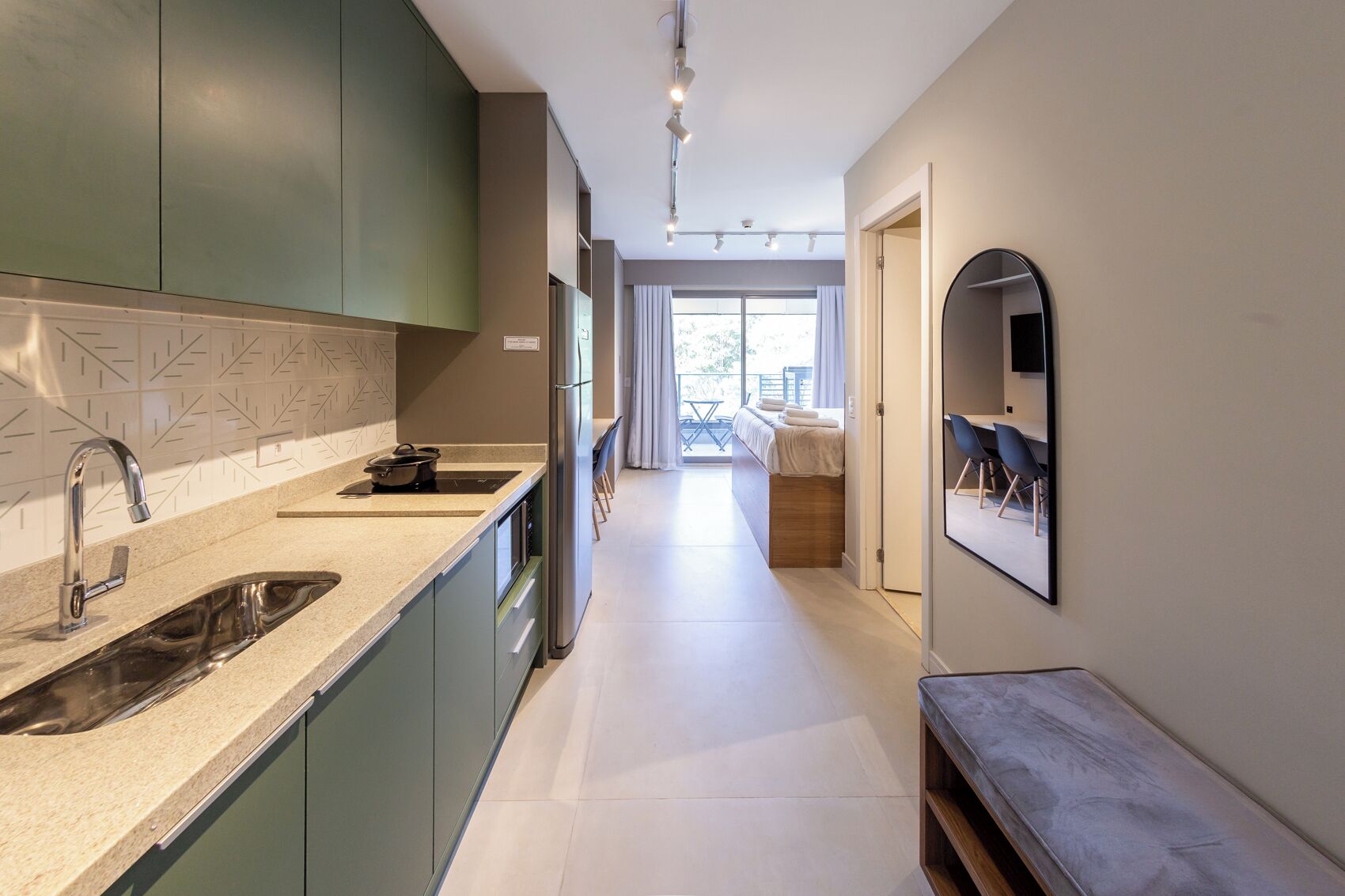 A modern kitchen with a built-in oven, a sink, and a dining area with a bench.