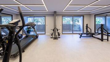 Un gimnasio moderno con equipo de ejercicio, ventanas amplias y un suelo claro y luminoso.