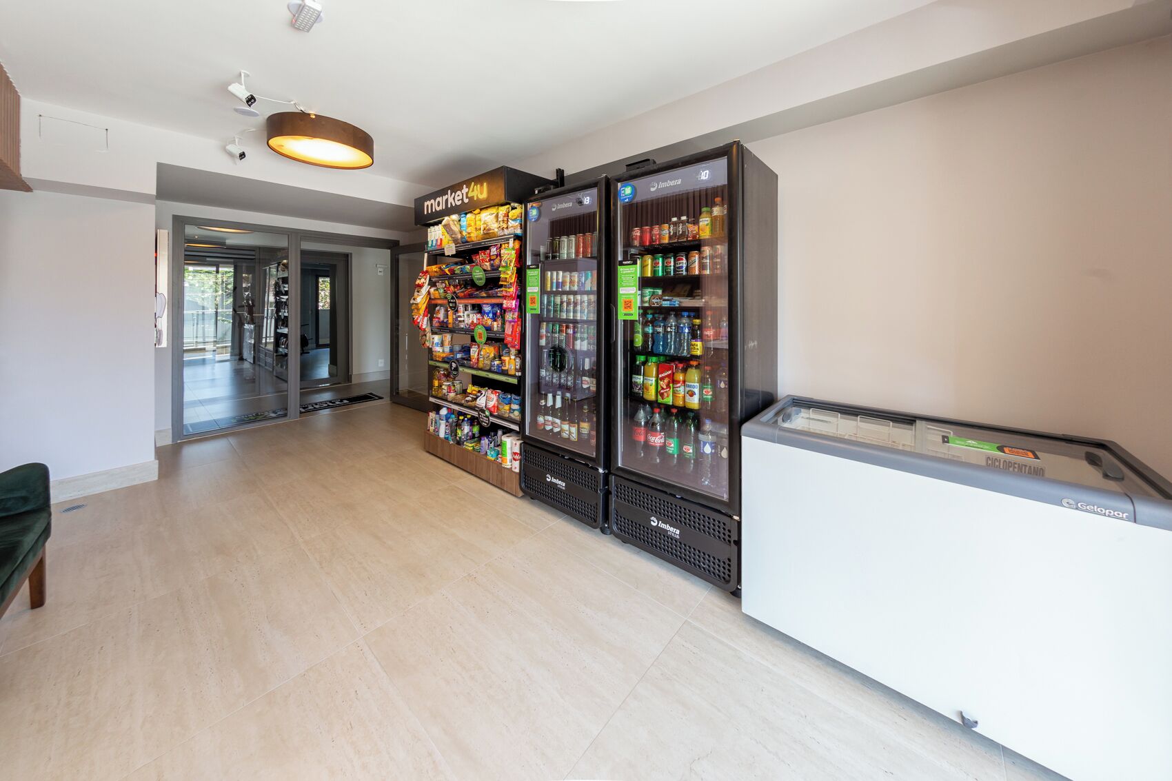 A hallway with a vending machine stocked with snacks and beverages, a bench, and a reception area with a counter.