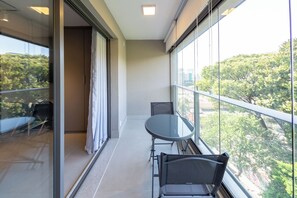 A balcony with a glass door, a round table, and two chairs. - Caraibas by Bhomy (São Paulo)
