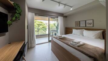 Una habitación de hotel moderna con cama, escritorio y un ventanal grande.