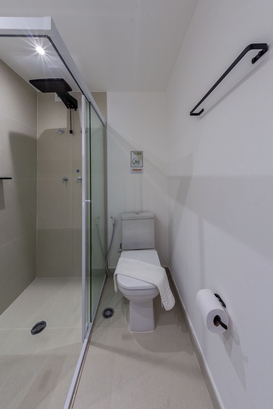 A modern bathroom with a glass-enclosed shower, a toilet, and a towel rack.