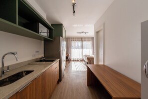 A modern kitchen with a built-in oven, a sink, and a wooden countertop. - Caraibas by Bhomy (São Paulo)