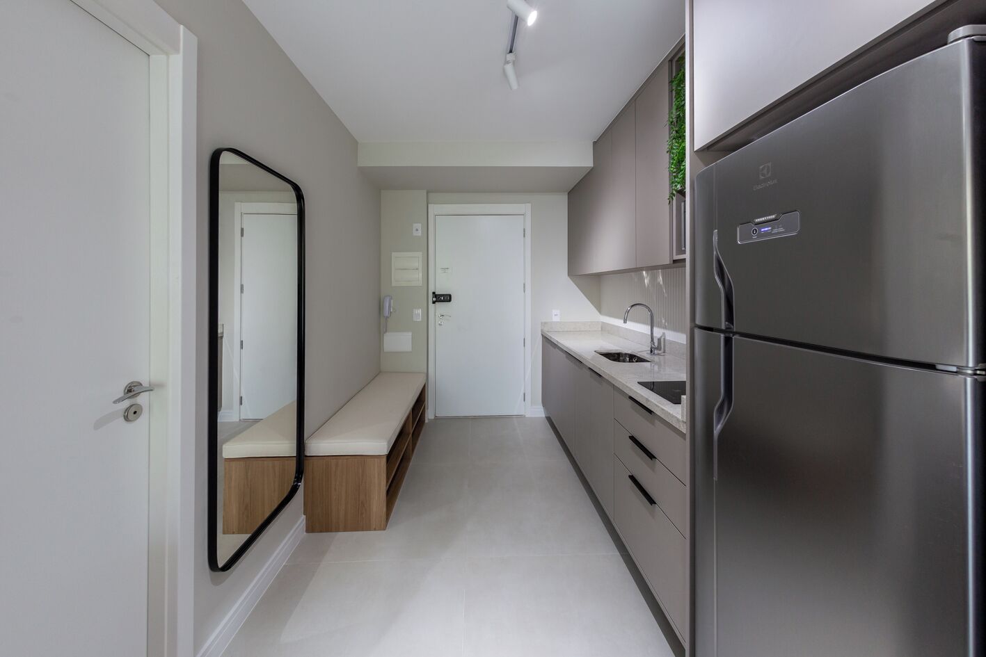 A modern kitchen with a stainless steel refrigerator, a built-in oven, and a sink.