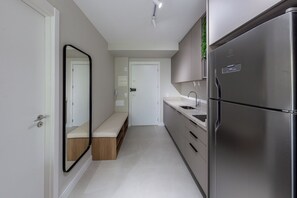 Una cocina moderna con un refrigerador de acero inoxidable, horno integrado y un lavamanos.