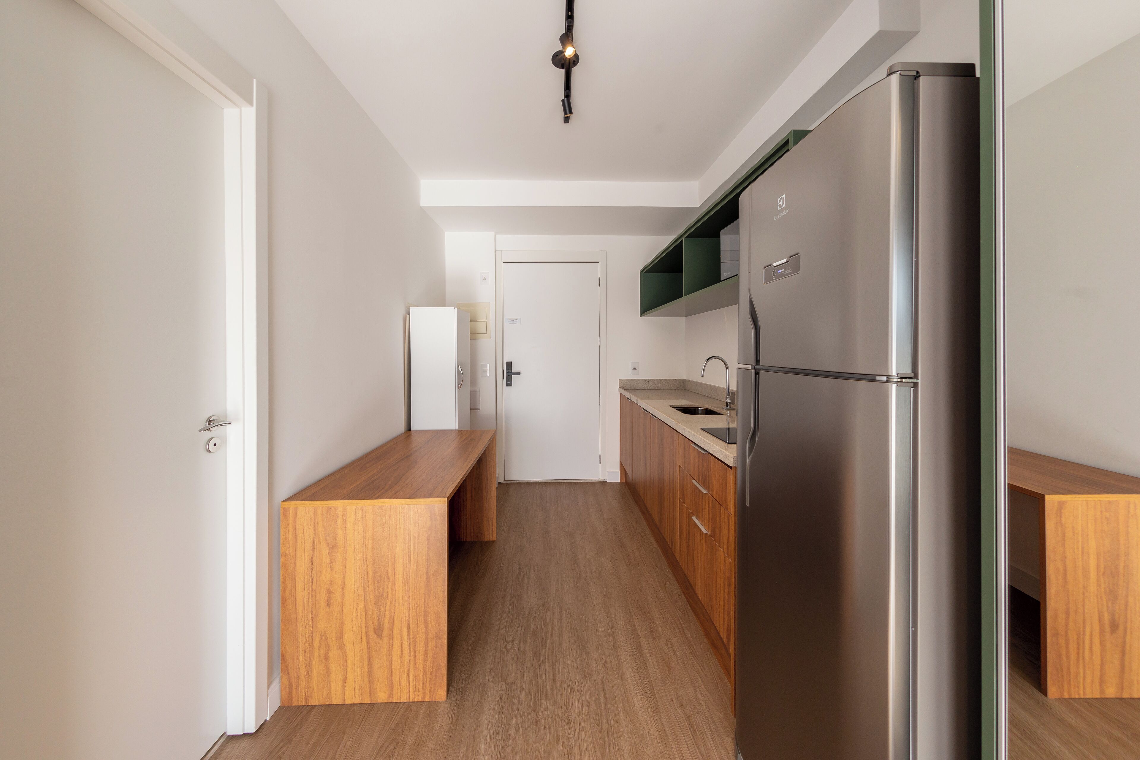 A modern kitchen with a stainless steel refrigerator, wooden cabinets, and a built-in oven.
