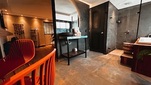 A modern kitchen with a black countertop, a red chair, and a wooden table. - Luxury Sense II (Medellín)
