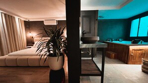 A modern bedroom with a large bed, a potted plant, and a bedside table. - Luxury Sense II (Medellín)