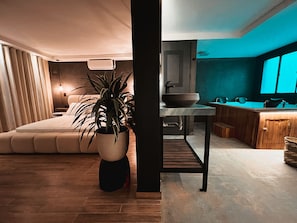 Ein modernes Schlafzimmer mit einem großen Bett, einer Topfpflanze und einem Nachttisch.