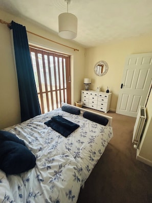 A bedroom with a bed, a dresser, a mirror, and a door. - Welcome to The Dingle (Walton)