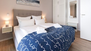 A hotel room with a bed, a bedside table with a lamp, a wardrobe, and a painting on the wall. - Parkidylle mit Sauna (Lübeck)