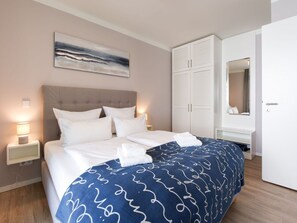 Ein Hotelzimmer mit Bett, Nachttisch mit Lampe, Kleiderschrank und einem Bild an der Wand.