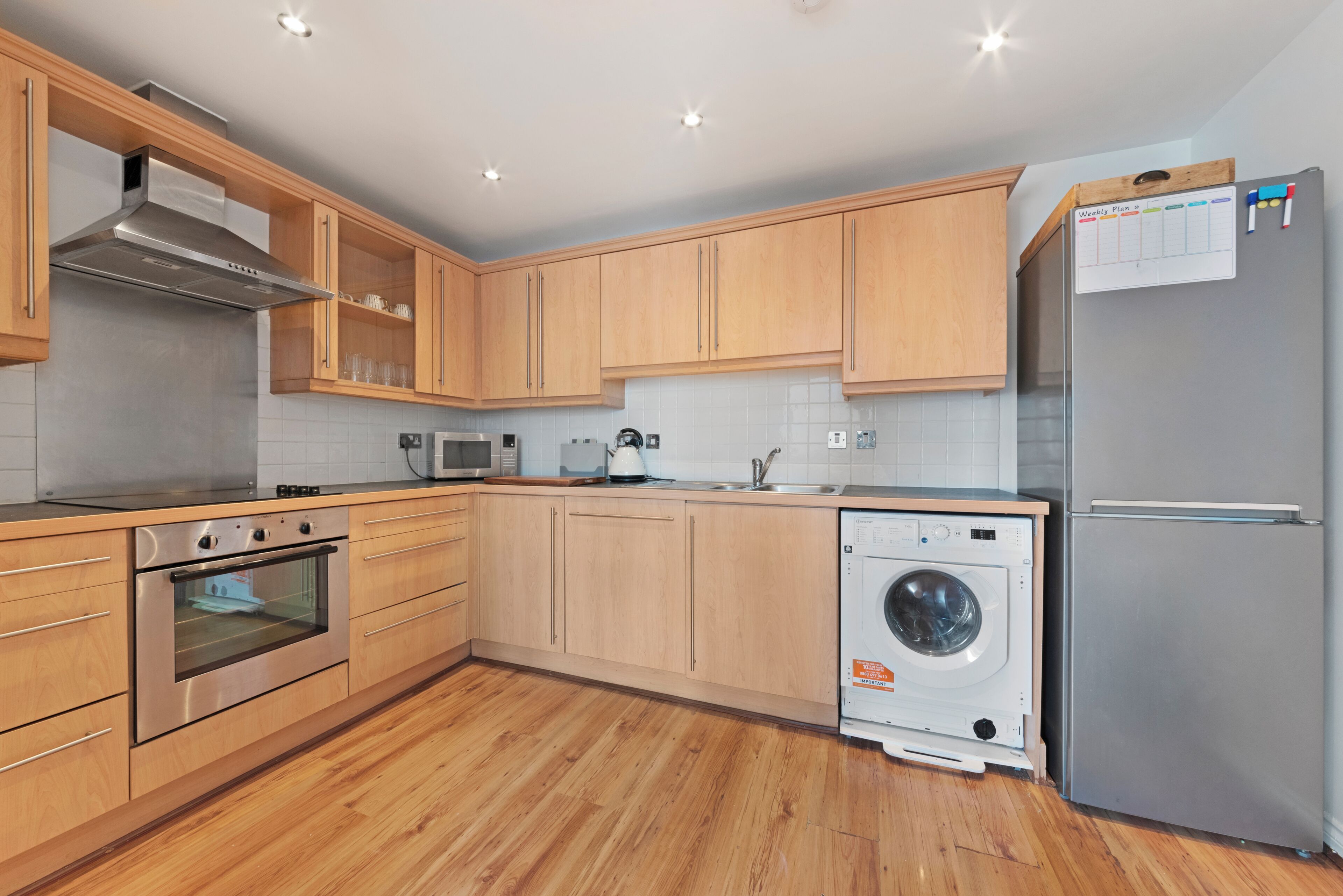 Una cocina moderna con armarios de madera, electrodomésticos de acero inoxidable y lavadora integrada.