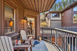 A wooden deck with two Adirondack chairs, a small table, and a birdhouse. - Walk to Lifts & Main St | Hot Tub (Breckenridge)