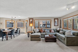A spacious living room with a dining area, large windows, and a chandelier. - Walk to Lifts & Main St | Hot Tub (Breckenridge)