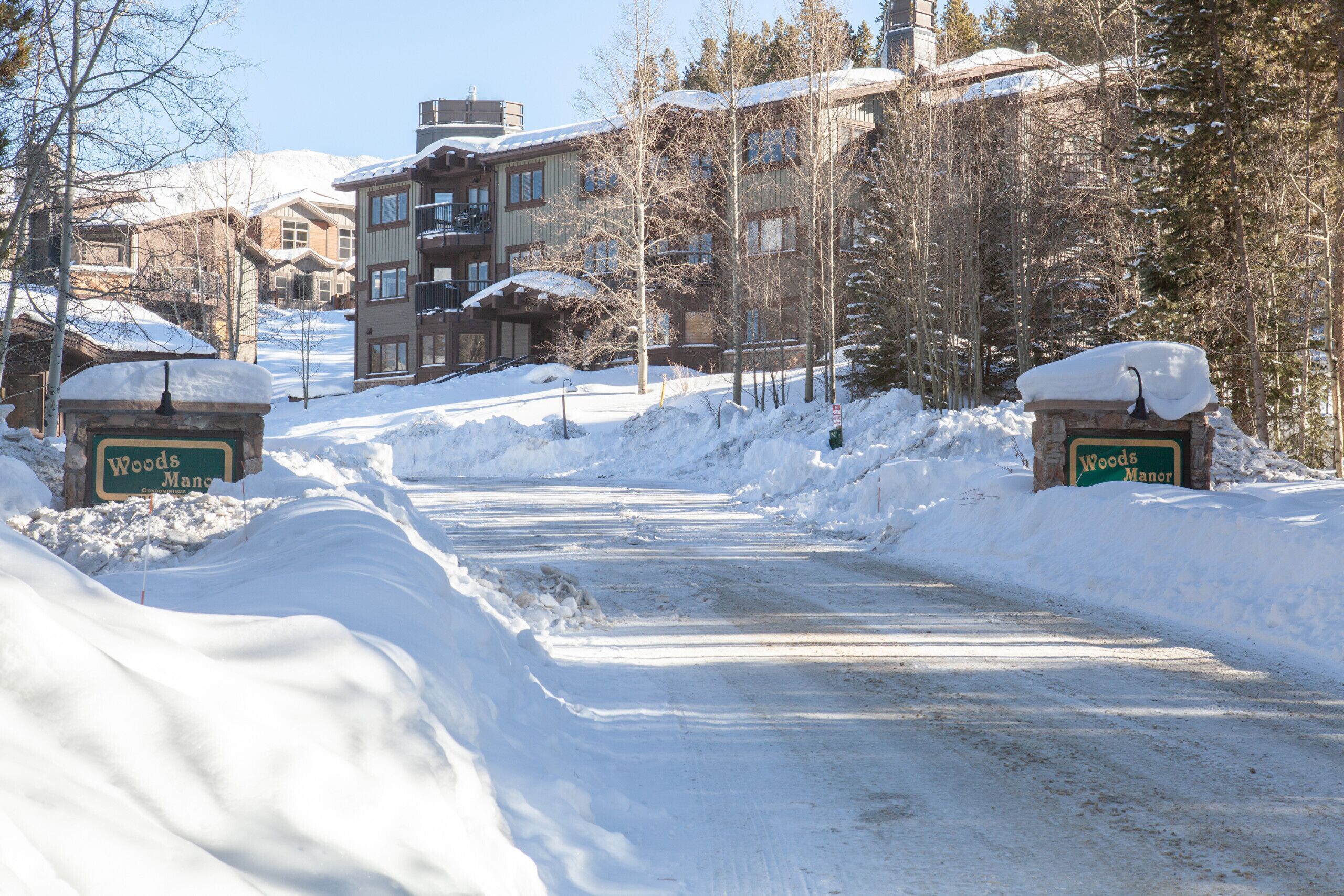 A snow-covered road leading to a building with a sign that reads "Woods Manor."