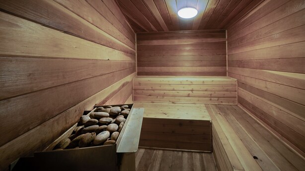 A wooden sauna with benches and a stone-filled container. - Walk to Lifts & Main St | Hot Tub (Breckenridge)