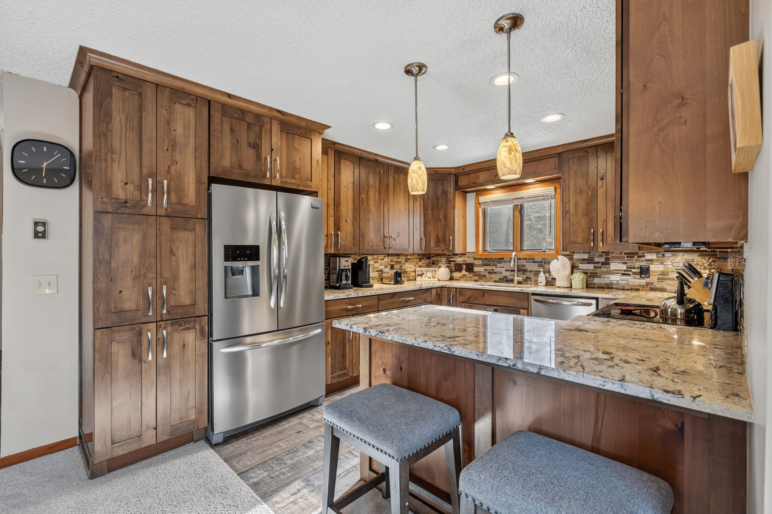 A modern kitchen with wooden cabinets, stainless steel appliances, and a marble countertop.
