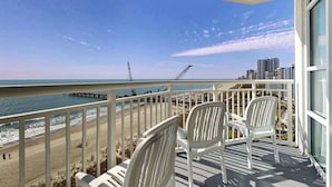 Een balkon met witte stoelen met uitzicht op een strand en de oceaan.