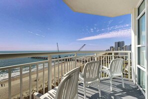A balcony with white chairs overlooking a beach and ocean. - Carolinian Beach Resort 0933 (Myrtle Beach)