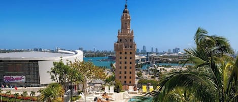 A hotel with a pool, palm trees, and a view of a city skyline.
