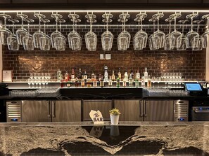 A bar area with a brick wall, hanging wine glasses, and a variety of liquor bottles. - Modern Studio with Balcony in Downtown Miami (Miami)