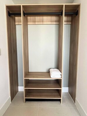 A walk-in closet with wooden shelving and a hanging rod. - Modern Studio with Balcony in Downtown Miami (Miami)