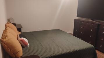 Une chambre à coucher avec un lit, une commode et un téléviseur à écran plat.