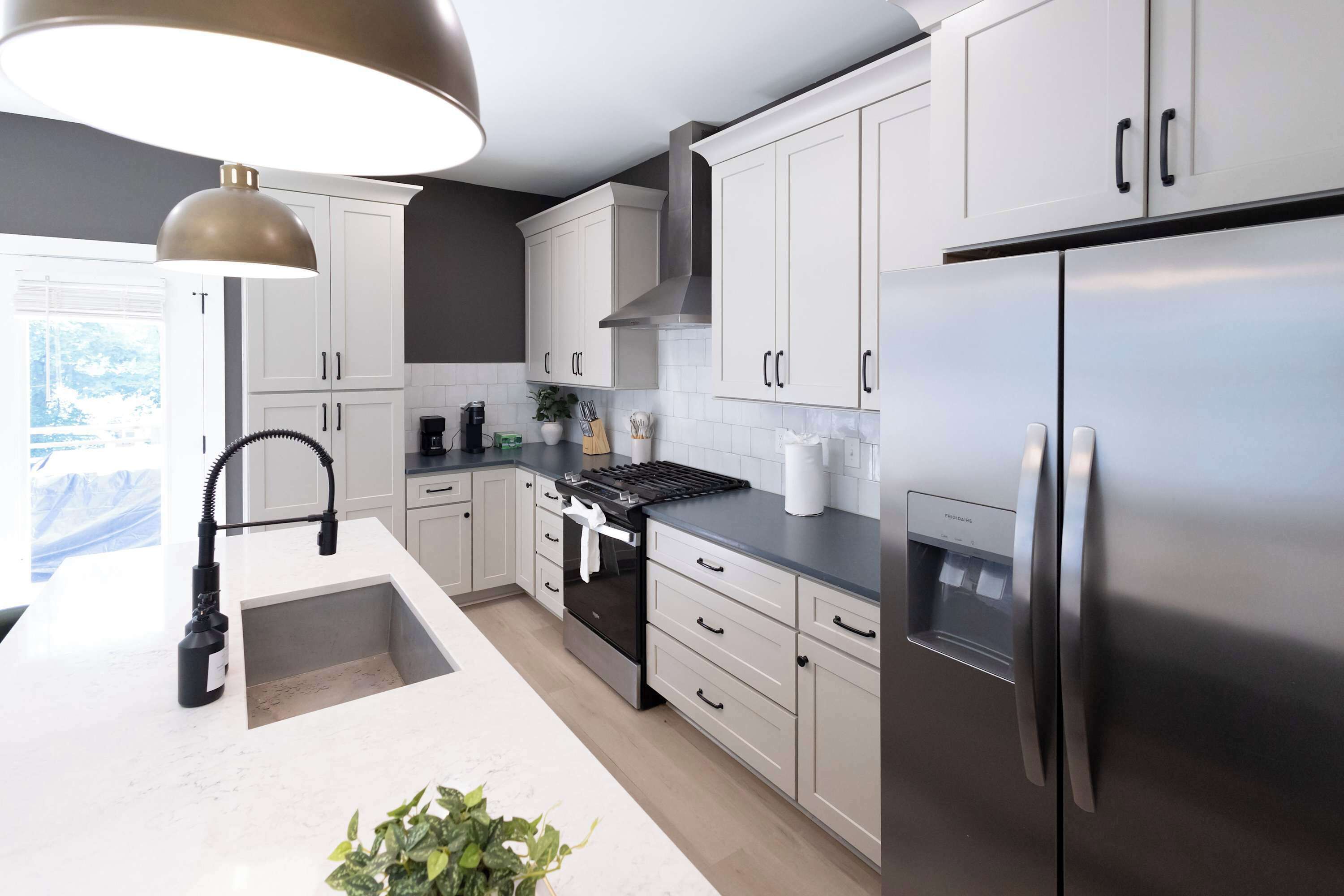 A modern kitchen with white cabinetry, a stainless steel refrigerator, and a built-in oven.