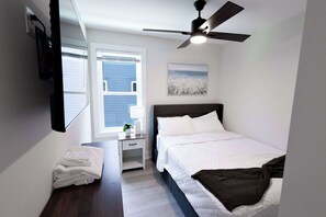 A bedroom with a bed, a nightstand, a ceiling fan, a window, and a wall-mounted artwork. - 8 Min to Duke + Downtown | Back Deck (Durham)