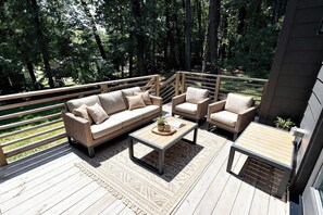 An outdoor deck with a sofa set, two armchairs, a coffee table, and a small table with a plant. - 8 Min to Duke + Downtown | Back Deck (Durham)
