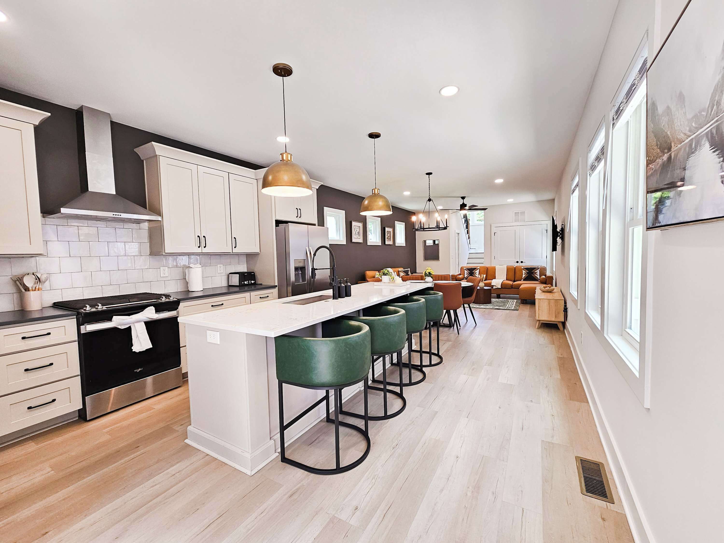 A modern kitchen with a central island, bar stools, and pendant lighting.